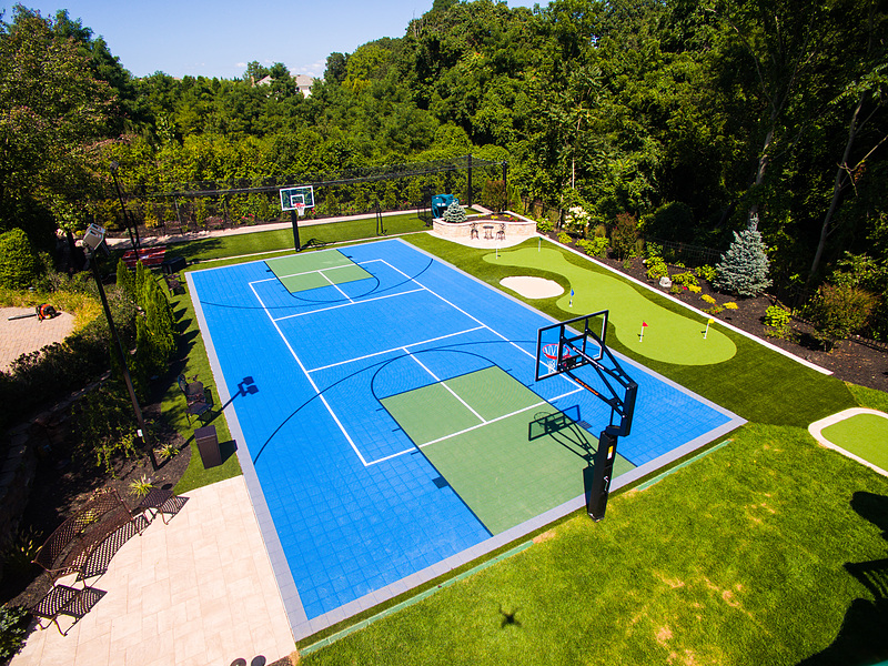 Blue VersaCourt multi-game court in a landscaped garden